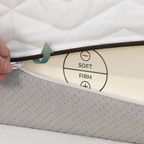 Hand adjusting a mattress setting dial on a mattress with soft and firm labels.